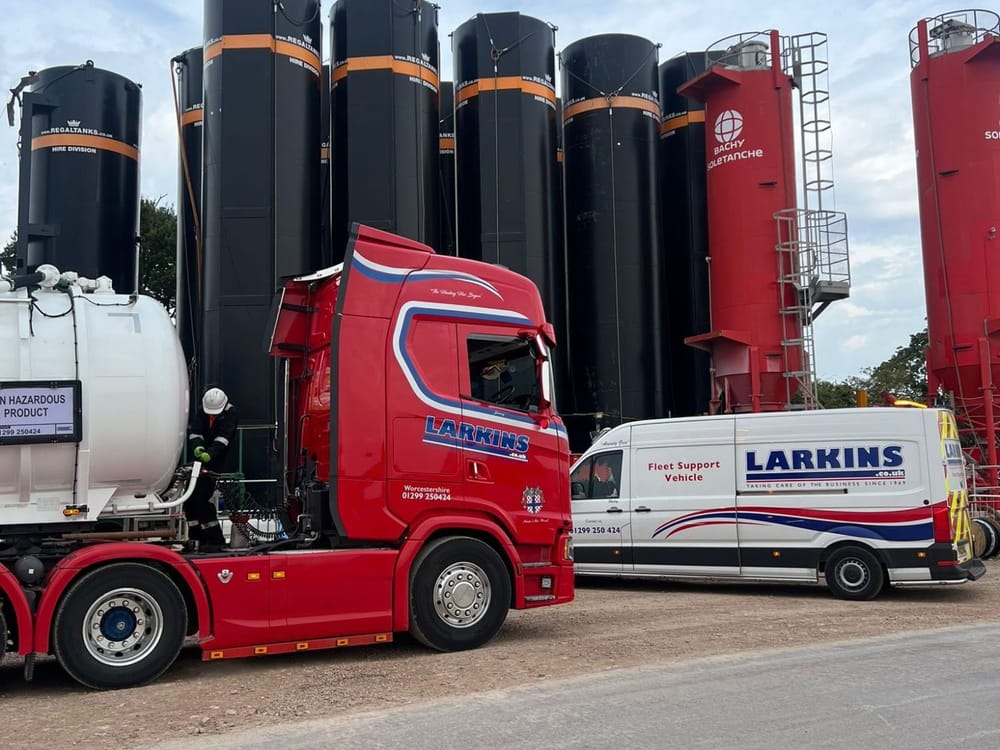 Larkins tanker discharging beside storage silos on an industrial site, with a fleet support van alongside